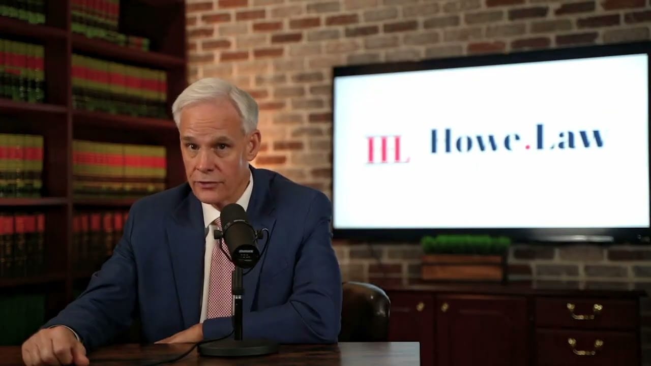 Atlanta personal injury lawyer speaking at desk with Howe.Law logo on screen