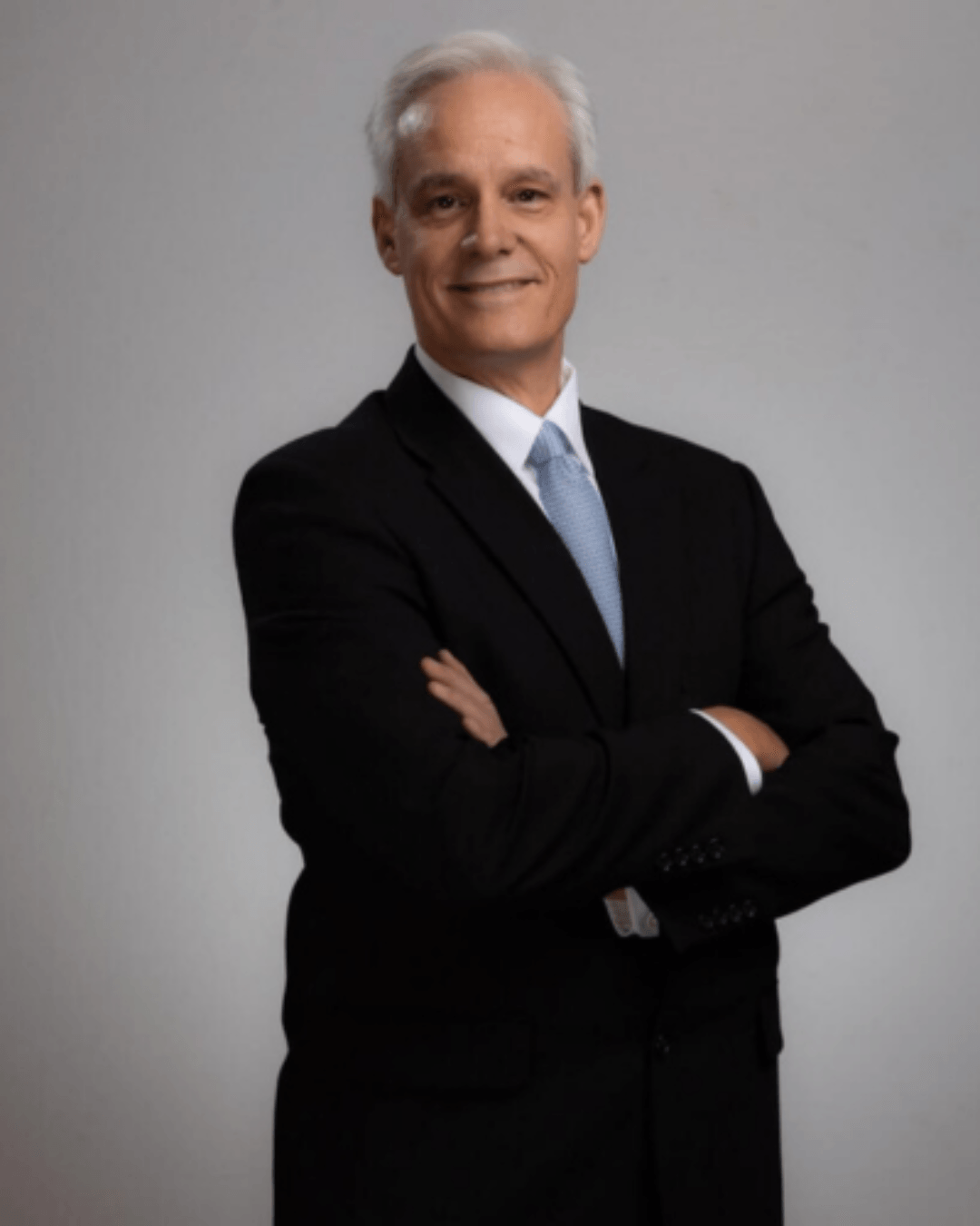 Male attorney in black suit and blue tie with arms crossed